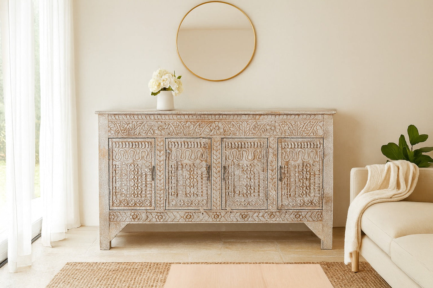 Decorative wooden sideboard in a living room with a round mirror and a sofa.
